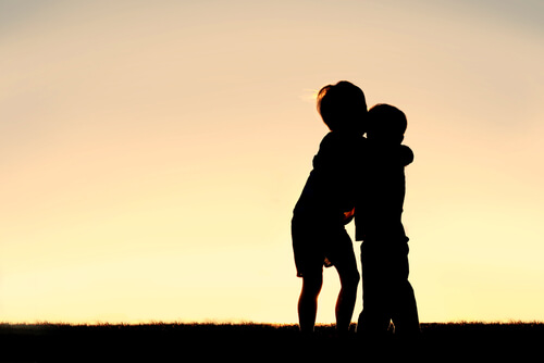 Hermano mayor abrazando a su hermano pequeño al atardecer