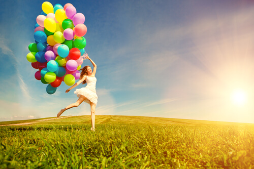 Mujer feliz con globos de colores en el campo