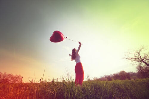 Mujer con globo de corazón disfrutando de la vida al aire libre