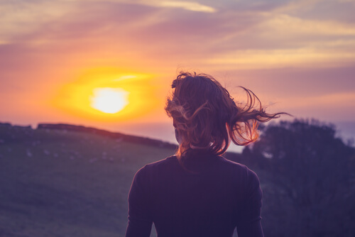 Mujer mirando el atardecer en la montaña