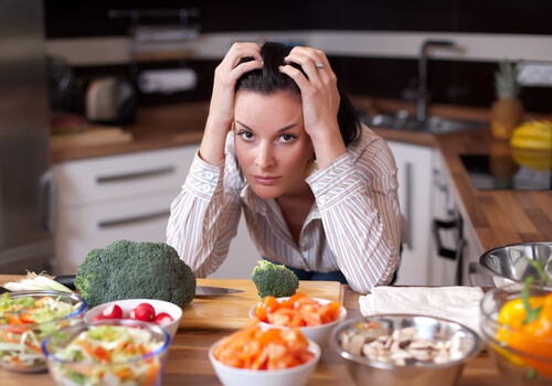 Mujer nerviosa con mucha comida en la mesa