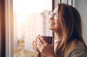 Mujer sonriendo con una taza de té en las manos para representar el JOMO