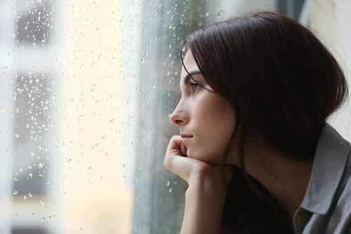 Mujer triste por un adiós mirando por la ventana
