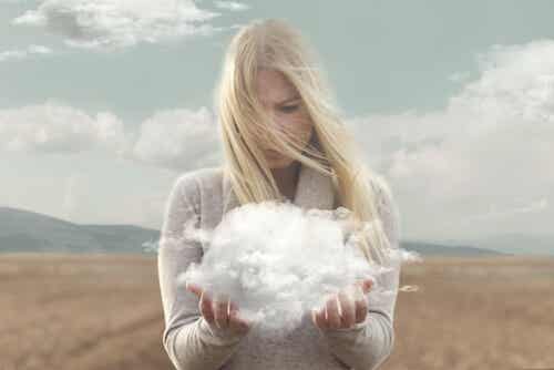 Mujer sujetando una nube con sus manos pensando en alejarse para tomar perspectiva