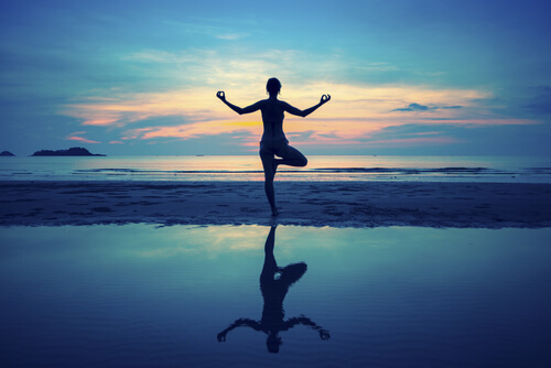 Mujer haciendo yoga en la playa