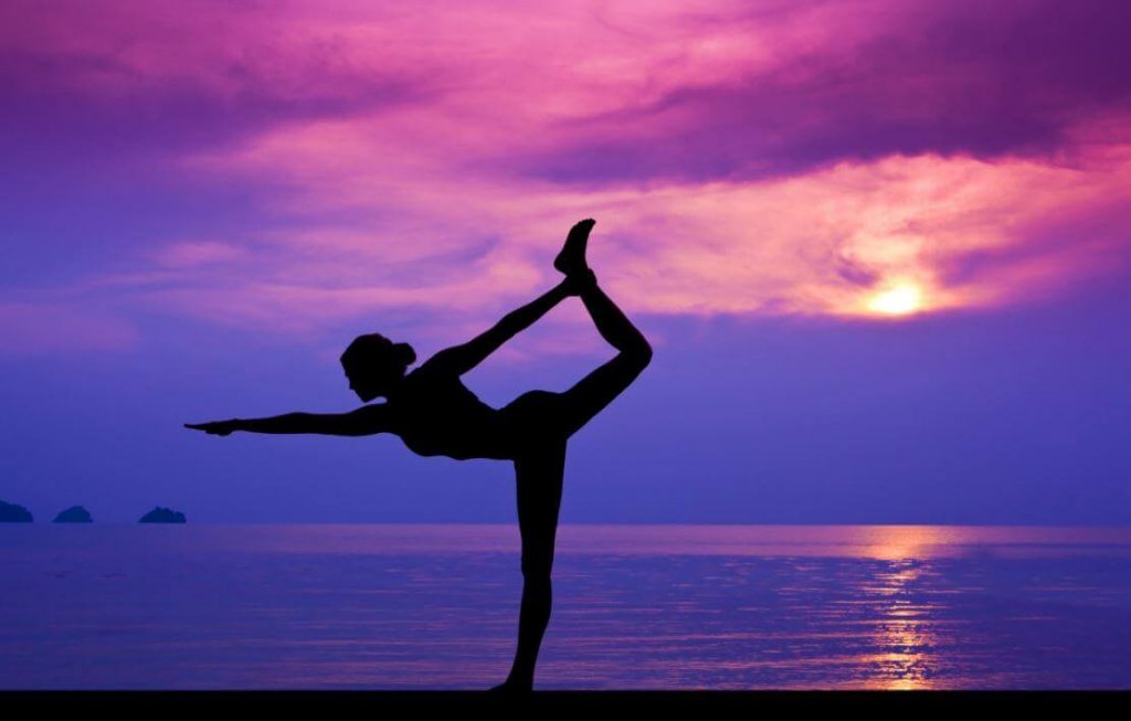 Mujer disfrutando de los beneficios del yoga en la playa