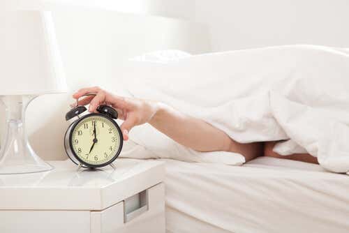 Hombre apagando despertador porque quiere consejos para dormir mejor