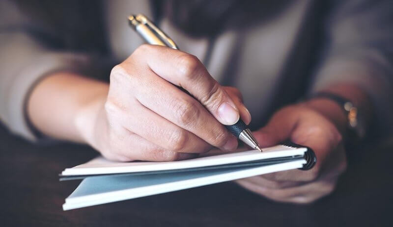 Hombre escribiendo en una libreta fortalezas para buscar trabajo