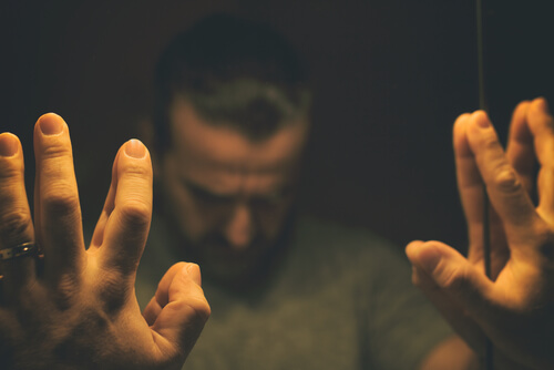 Hombre ante une spejo con pensamientos distorsionados