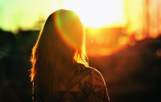 Jente med ryggen mot soloppgangen og tenker på å møte problemene sine