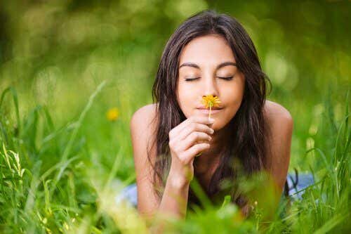 Mujer con una sonrisa oliendo una flor