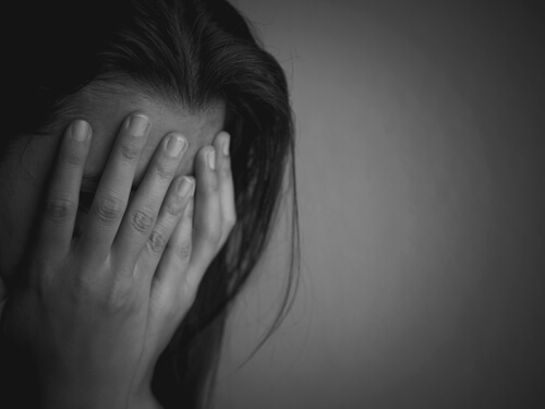 Mujer con manos en la cara asustada por asalto