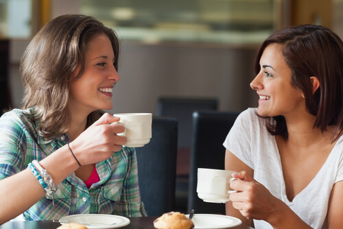 Amigas sonriendo mientras toman un café