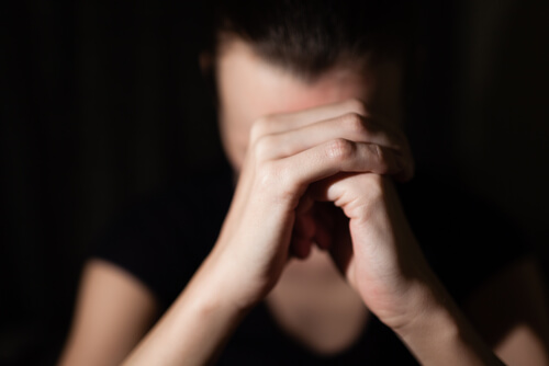 Mujer con manos entrelazadas pidiendo perdón