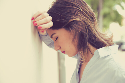 Mujer estresada apoyando la cabeza en la pared