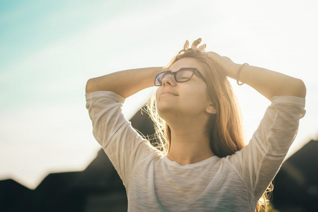 Mujer con los ojos cerrados practicando el optimismo