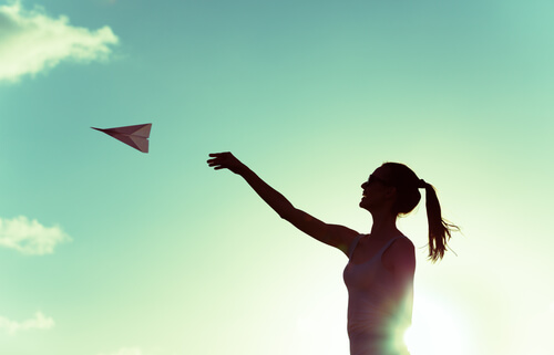 Mujer jugando con un avión de papel