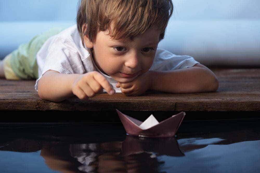 Niño jugando con barco de papel representando los beneficios de pensar en voz alta