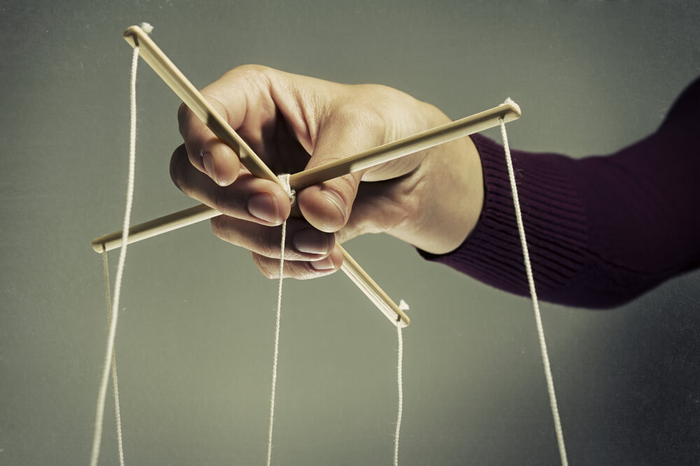 hombre que sostiene una marioneta y hace chantaje emocional