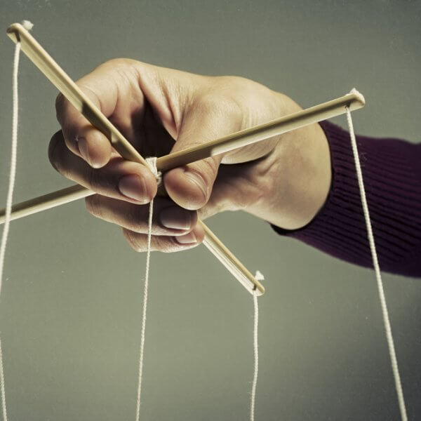 Mano manipulando las cuerdas de una marioneta para representar a un manipulador