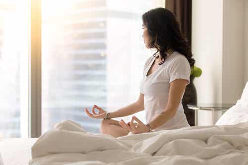 Kvinde mediterer i seng