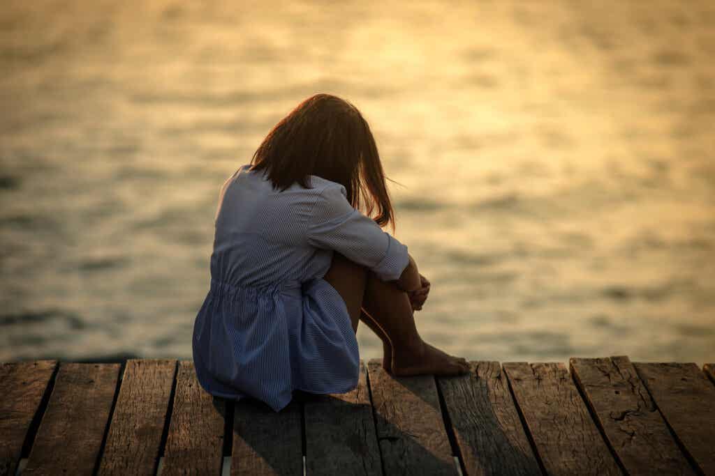 Kvinde sidder på bro og oplever at være afhængig af ulykkelighed