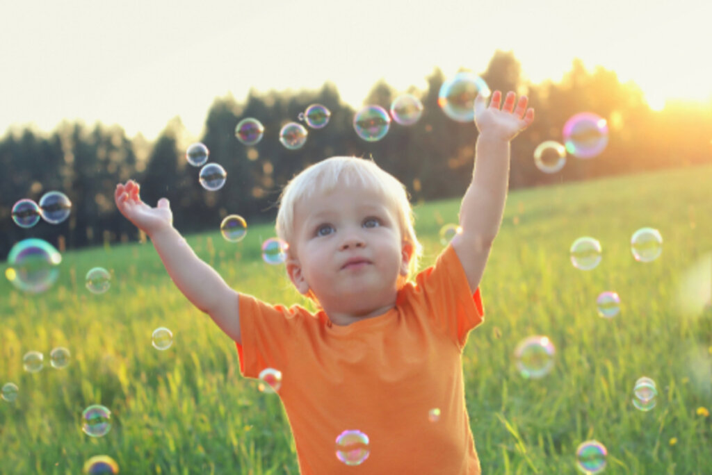 Bambino che gioca con le bolle di sapone che necessita della somministrazione dell'ormone della crescita