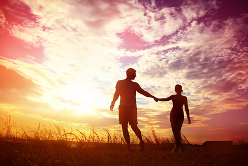 Pareja agarrada de la mano al atardecer