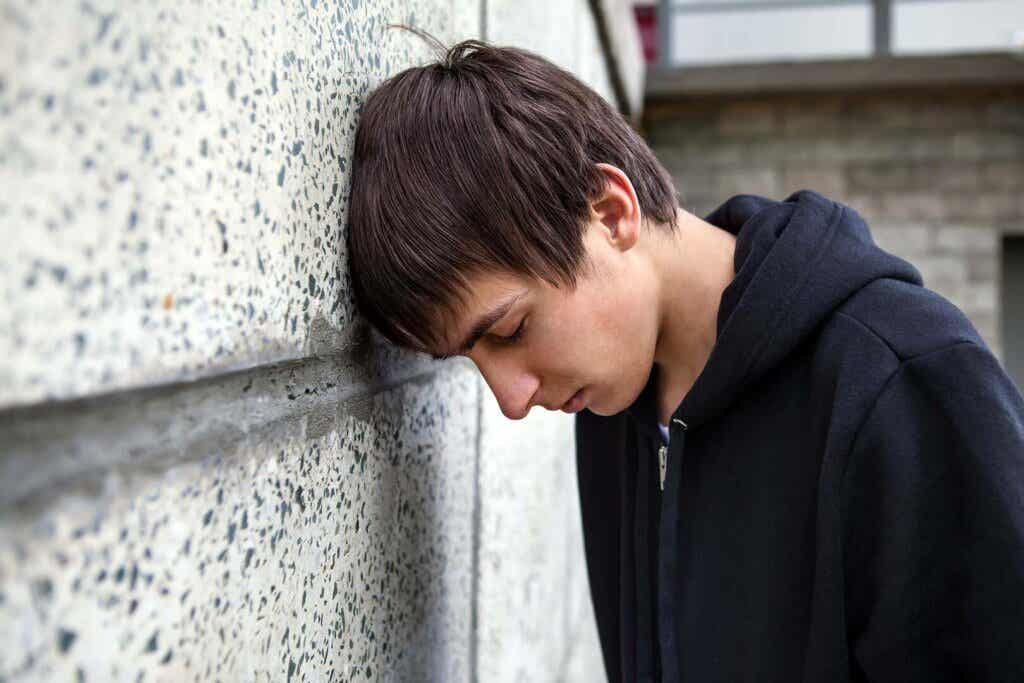 sad boy leaning head on wall