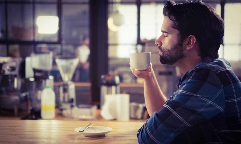 hombre oliendo taza cafe