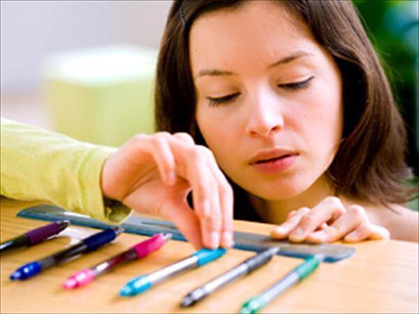 Mujer con trastorno obsesivo compulsivo ordenando bolígrafos