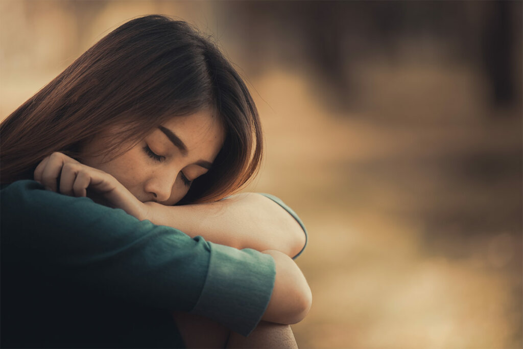 Mujer triste sentada pensando en ¿Cómo afecta una infancia difícil a las relaciones adultas?