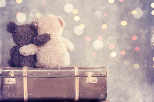 Teddy bears cuddling on top of a suitcase