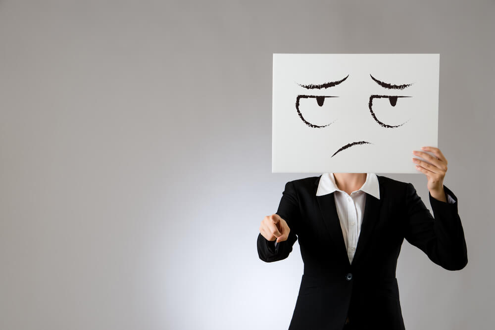 Mujer con un cartel con una cara triste en la cara