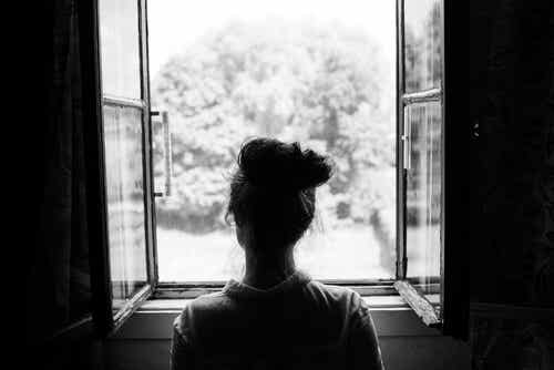 Mujer mirando por la ventana pensando en las consecuencias de ser pesimista
