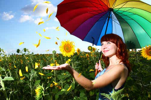 Mujer con un paraguas de colores demostrando felicidad