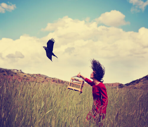 Mujer liberando un pájaro de la jaula