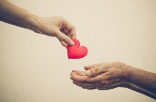 Mano dando un corazón a otra como gesto de ayuda