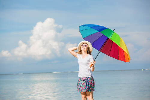 Mulher feliz com um guarda-chuva colorido.