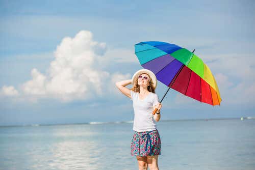 Frau mit buntem Sonnenschirm am Strand