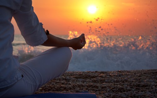 Mujer haciendo meditación junto al mar