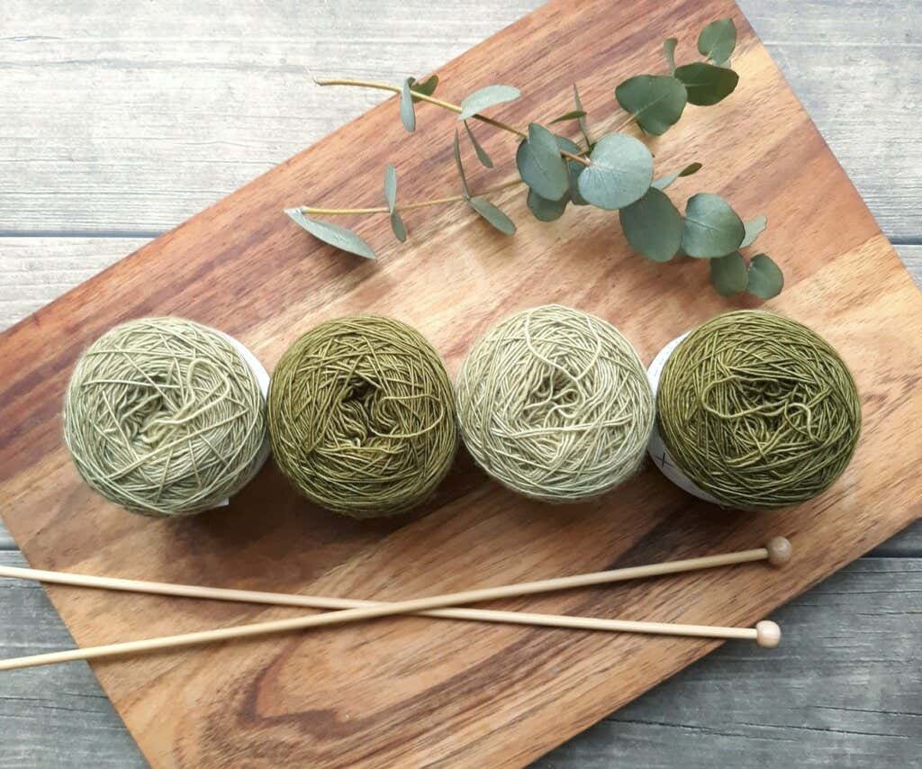 Gomiti di lana verde e ferri da maglia lanoterapia. 