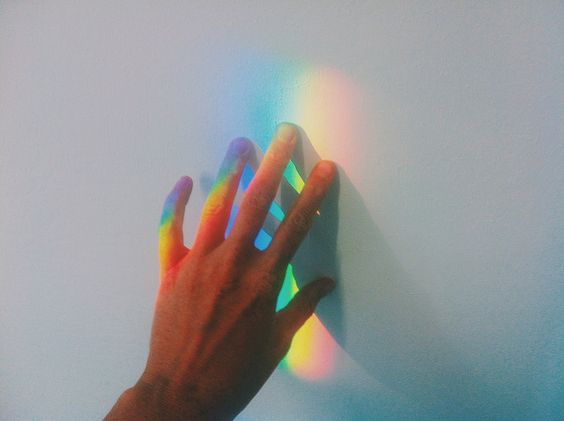 Main touchant la lumière arc-en-ciel