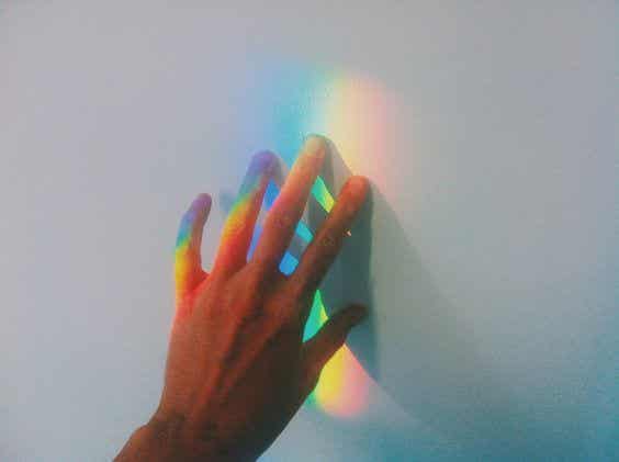 mano tocando la luz del arco iris representando a la persona sensible