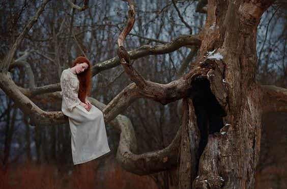 Mujer triste en un árbol pensando en sus demonios