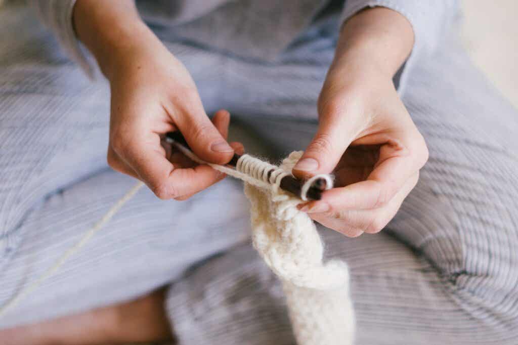Donna che lavora a maglia nel suo letto. 