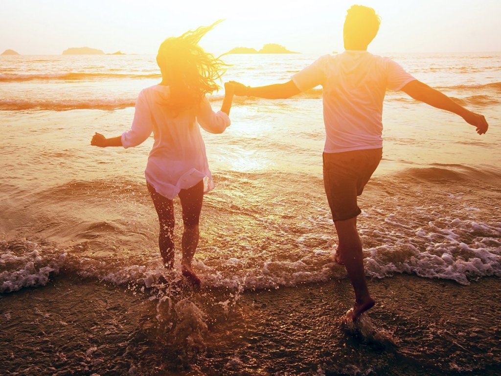Pareja dándose la mano en la playa