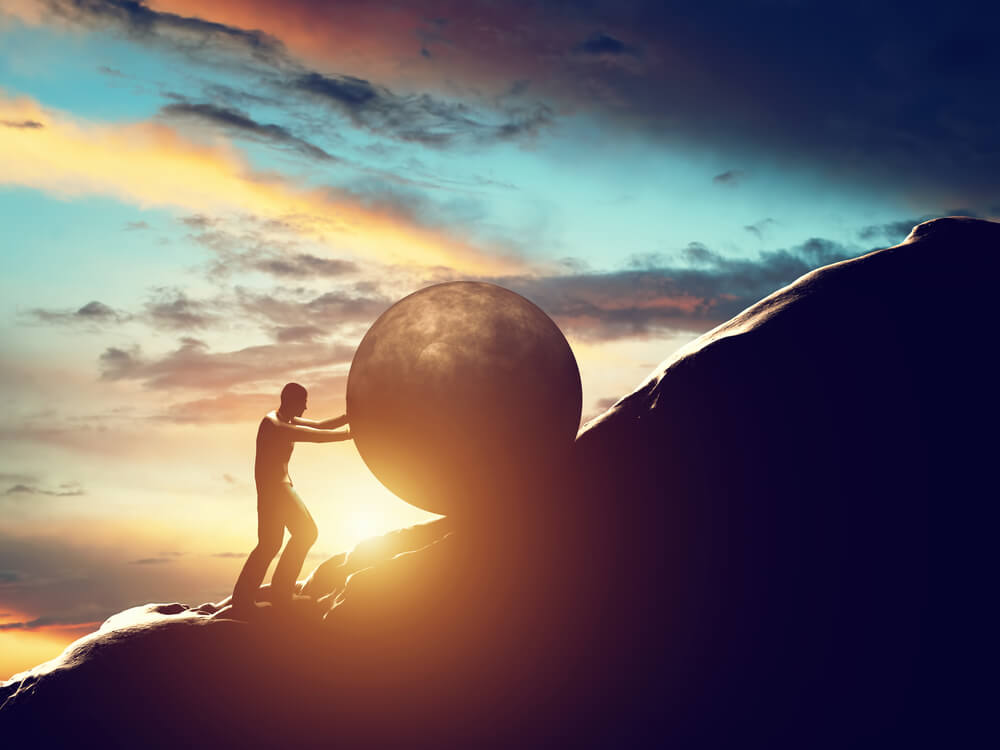 hombre-empujando-una-piedra-redonda-enorme el valor del esfuerzo