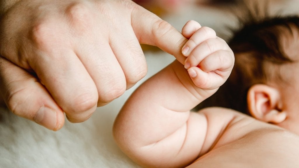 Bebé agarrando dedo de su padre
