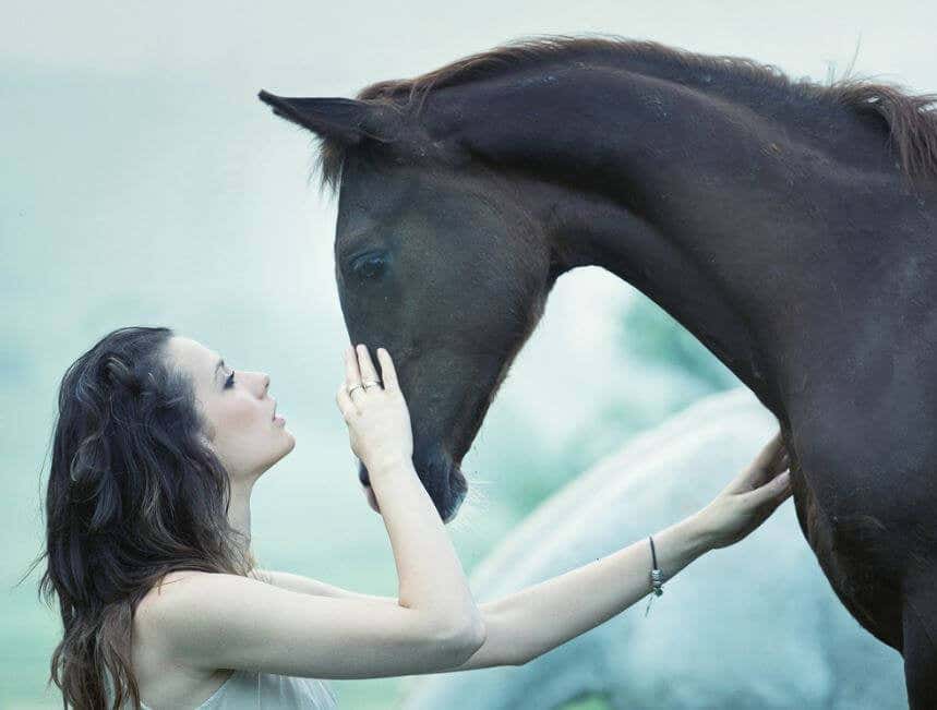 Mujer acariciando la cara de un caballo mientras lo mira a los ojos